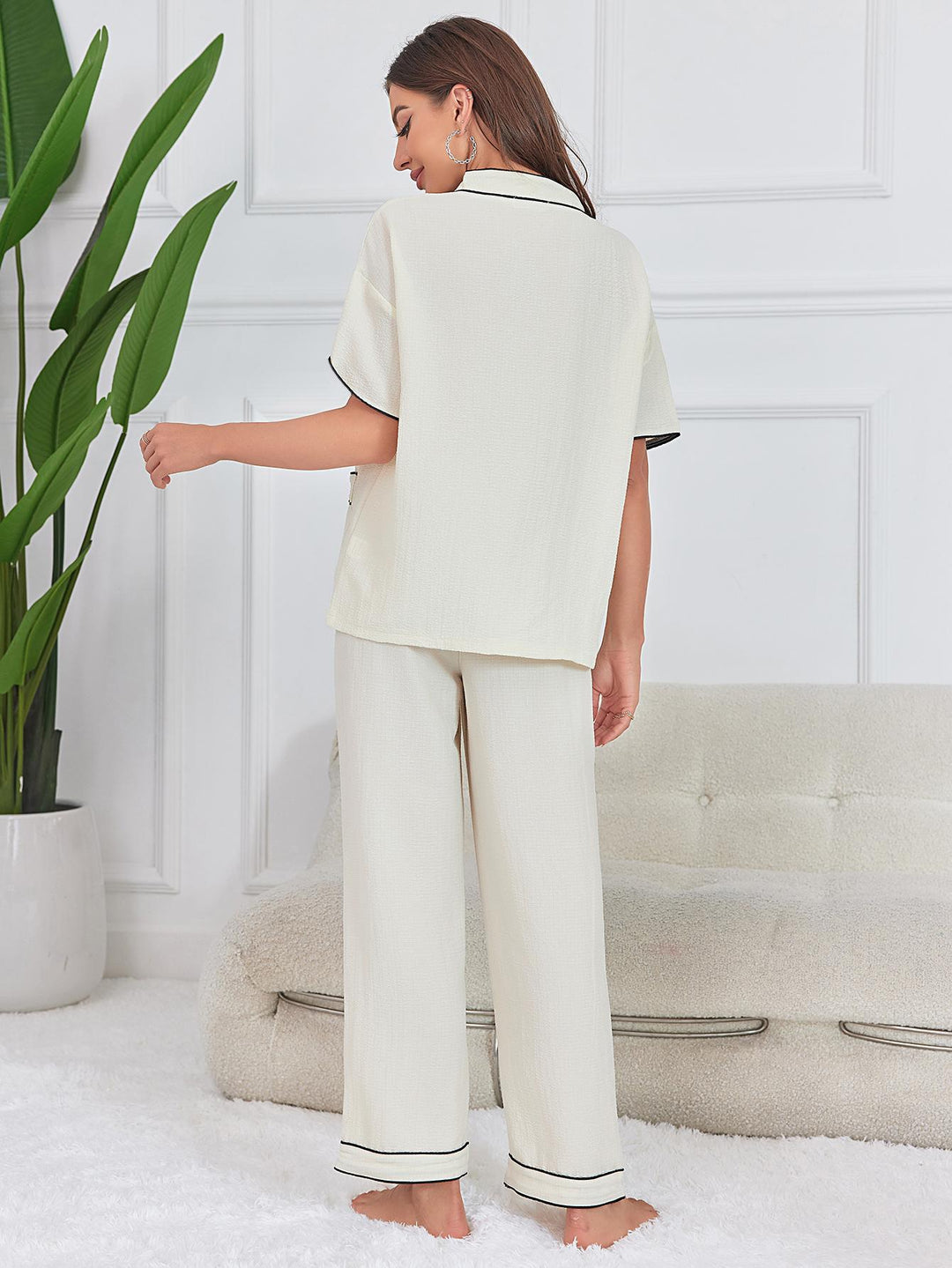 Dames tweedelige set met top met korte mouwen, V-hals, knoopsluiting, contrasterende biezen en wijde pijpen